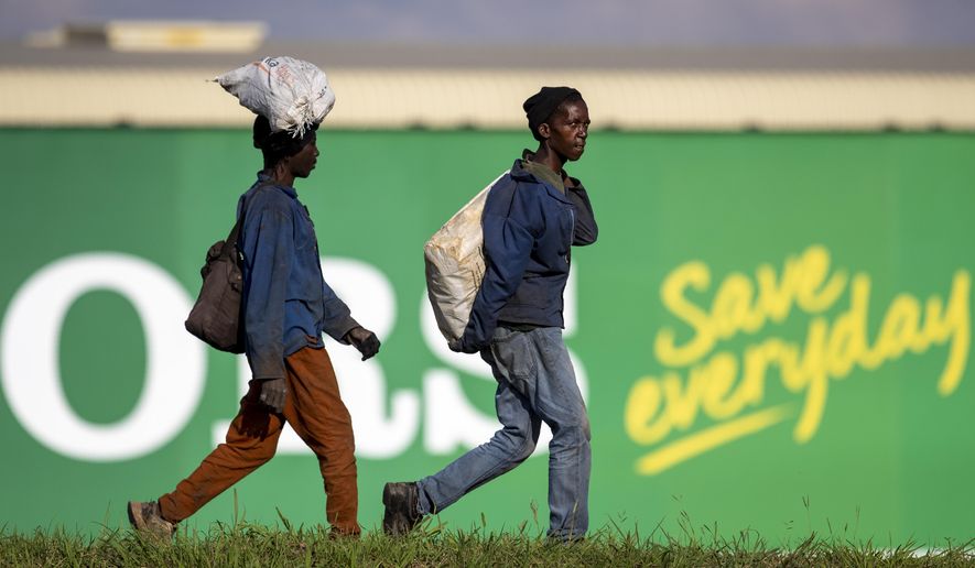 Men carrying recycling material walk in the industrial area in Daveyton, east of Johannesburg, South Africa, Tuesday, March 24, 2020, a day after it was announced that South Africa will go into a nationwide lockdown for 21 days from Thursday to fight the spread of the new coronavirus. The highly contagious COVID-19 coronavirus can cause mild symptoms, but for some it can cause severe illness including pneumonia. (AP Photo/Themba Hadebe)