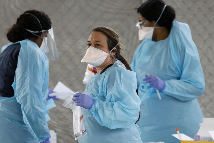 Raeanne Castillo, center, with Roper St. Francis Healthcare holds specimen collection kits at the hospital's North Charleston office Monday, March 16, 2020, in North Charleston, S.C. Roper St. Francis Healthcare is providing drive-through specimen collecting for patients suspected of having COVID-19 or flu who have already been screened by a Virtual Care provider. (AP Photo/Mic Smith)