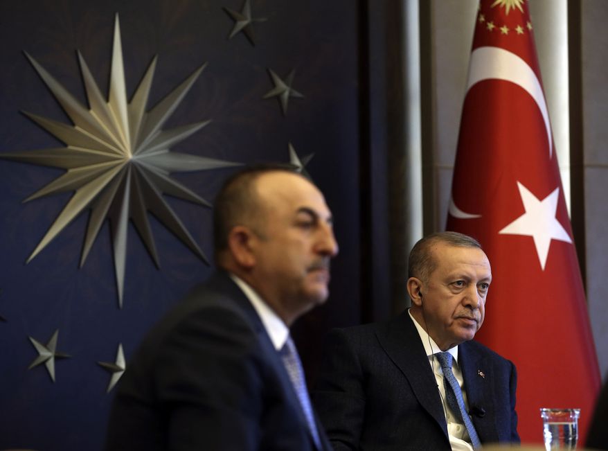 Turkish President Recep Tayyip Erdogan, right, flanked by Foreign Minister Mevlut Cavusoglu, participates in a teleconference with G-20 leaders amid the coronavirus outbreak, in Istanbul, Thursday, March 26, 2020. (Turkish Presidency via AP, Pool)