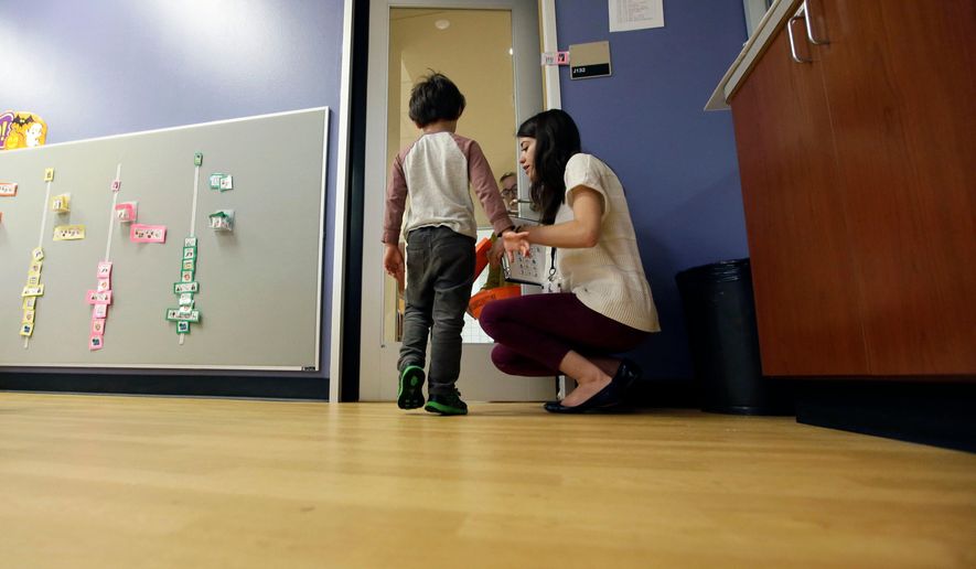 FILE - In this Monday, Oct. 24, 2016 file photo, Megan Krail helps a 4-year-old boy with Autism Spectrum Disorder practice trick-or-treating at The University of Texas at Dallas' Callier Center for Communication Disorders preschool class in Dallas. According to a report released by the Centers for Disease Control and Prevention on Thursday, March 26, 2020, about 1 in 54 U.S. children were identified as having autism in 2016. That's up from 1 in 59 children in 2014, and from 1 in 68 children in both 2010 and 2012. The study focused on 8-year-old children. (AP Photo/LM Otero)