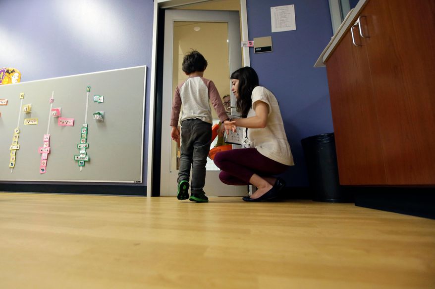 FILE - In this Monday, Oct. 24, 2016 file photo, Megan Krail helps a 4-year-old boy with Autism Spectrum Disorder practice trick-or-treating at The University of Texas at Dallas' Callier Center for Communication Disorders preschool class in Dallas. According to a report released by the Centers for Disease Control and Prevention on Thursday, March 26, 2020, about 1 in 54 U.S. children were identified as having autism in 2016. That's up from 1 in 59 children in 2014, and from 1 in 68 children in both 2010 and 2012. The study focused on 8-year-old children. (AP Photo/LM Otero)
