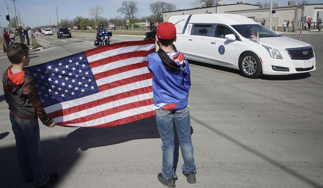 Brothers Colton and Ryder Stephens hold an American flag as they watch the procession for the body of Air Force Staff Sgt. Marshal D. Roberts Wednesday, March 25, 2020, in Tulsa, Okla.Roberts, 28, of Owasso, was killed on March 11 while deployed in support of Operation Inherent Resolve in Iraq. Roberts was a member of the 219th Engineering Installation Squadron, 138th Fighter Wing, headquartered in Tulsa. (Mike Simons/Tulsa World via AP)
