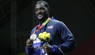 FILE - In this Sept. 29, 2019, file photo, silver medal winner Justin Gatlin, of the United States, smiles during the medal ceremony for the men&#39;s 100m event at the World Athletics Championships in Doha, Qatar. Gatlin and Jamaican Asafa Powell may be late 30-something sprinters but they feel as youthful as ever. There&#39;s no retirement talk even with the Tokyo Games delayed for a year due to the coronavirus. (AP Photo/Nariman El-Mofty, File)