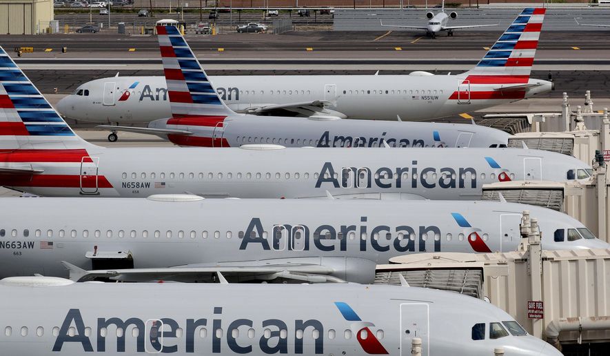 In this Wednesday, March 25, 2020, file photo, American Airlines jets sit idly at their gates as a jet arrives at Sky Harbor International Airport in Phoenix. (AP Photo/Matt York, File)