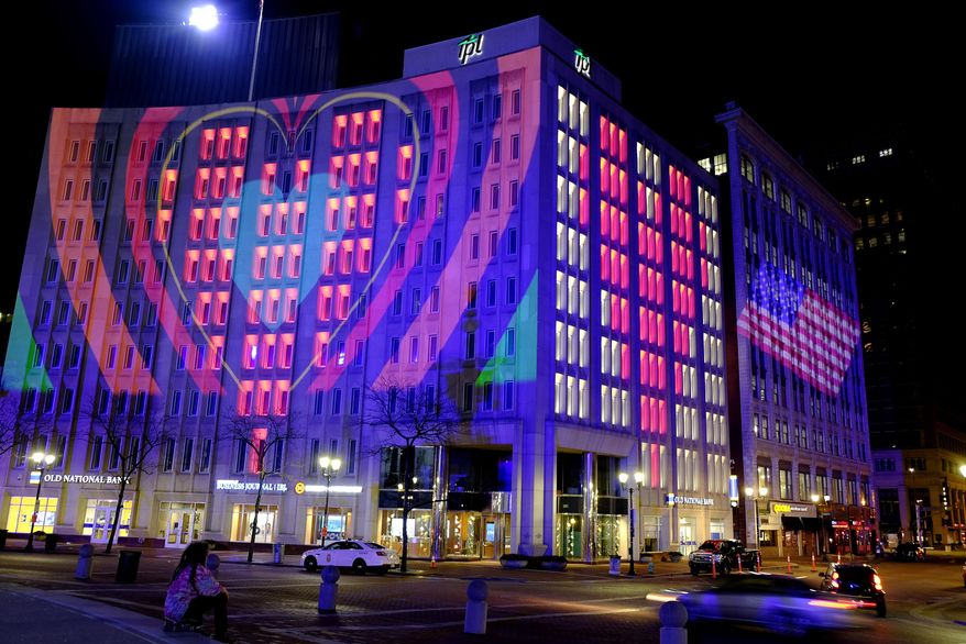 The Indianapolis Power & Light Company downtown headquarters is illuminated during a light display, Wednesday, March 25, 2020, in Indianapolis. The light display is controlled via a computer and uses energy-efficient, long-lasting bulbs to create a myriad of colors and movement. Gov. Eric Holcomb ordered state residents to remain in their homes to slow the spread of COVID-19, except when they are at work or for permitted activities. (AP Photo/Darron Cummings)
