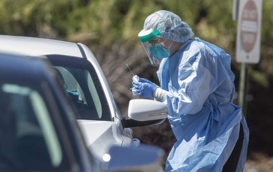 A medical worker administers a test for coronavirus at a drive-up testing center at GraceMed Health Clinic in Wichita, Kan., Wednesday, March 25, 2020. The new coronavirus causes mild or moderate symptoms for most people, but for some, especially older adults and people with existing health problems, it can cause more severe illness or death.(Travis Heying/The Wichita Eagle via AP)