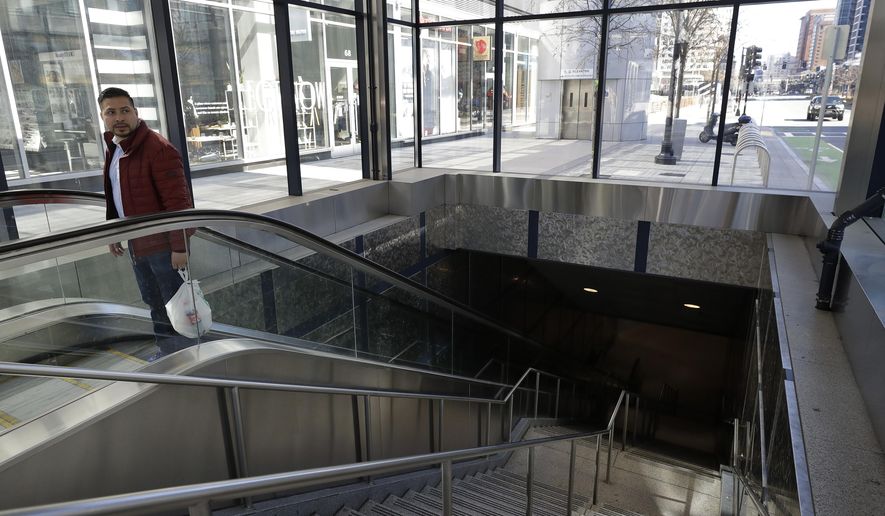 A man exits a subway station in the Seaport District, in Boston, Thursday, March 26, 2020. Many people are working from home while many businesses have closed indefinitely because of the coronavirus, leaving portions of the city nearly empty. The new coronavirus causes mild or moderate symptoms for most people, but for some, especially older adults and people with existing health problems, it can cause more severe illness or death. (AP Photo/Steven Senne)