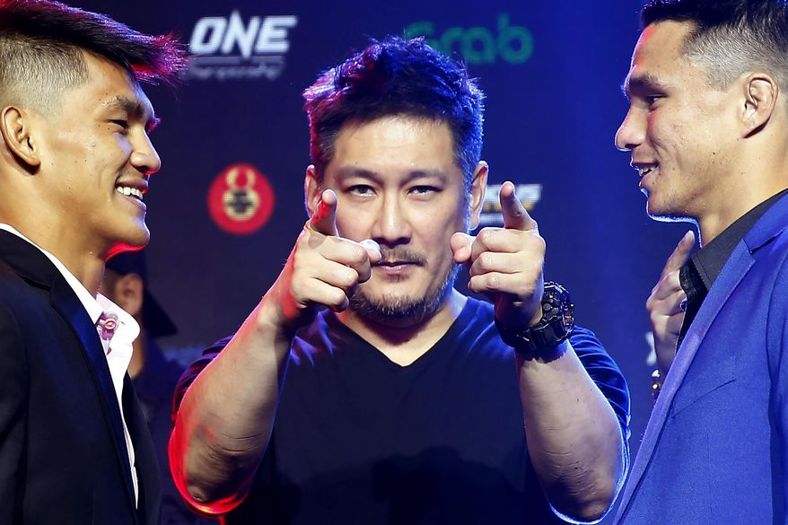 FILE - In this July 30, 2019, file photo, One Championship founder Chatri Sityodtong, center, gestures as Reece McLaren, right, of Australia and Danny Kingad, of the Philippines face off during the media presentation for this ONE Championship mixed martial arts fight dubbed: Dawn of Heroes, in suburban Pasay city, south of Manila, Philippines. As his mixed martial arts promotions go behind closed doors and audience free, Sityodtong says he's finding ways to thrive during the coronavirus pandemic that is shutting down sports around the globe. (AP Photo/Bullit Marquez, File)