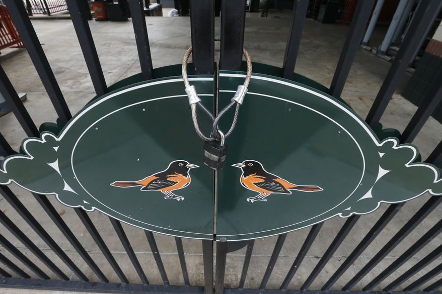 Locked gates and empty walkways are shown at Oriole Park at Camden Yards, home of the Baltimore Orioles baseball team, on what was to be opening day March 26, 2020, in Baltimore, Md. (AP Photo/Steve Helber)