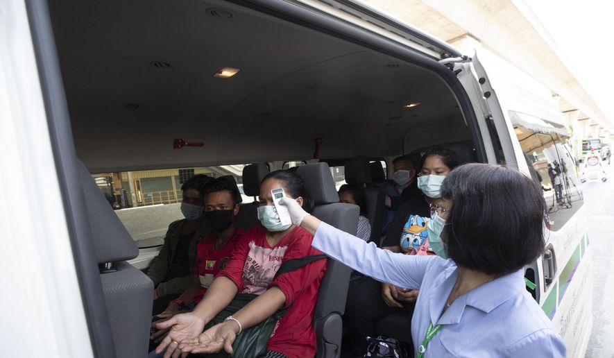 Health officer check temperature passenger in van at a health check point in Bangkok, Thailand, Thursday, March 26, 2020. It is the first day of month long state of emergency enforced in Thailand to allow its government to impose stricter measures to control the coronavirus that has infected hundreds of people in the Southeast Asian country. (AP Photo/Sakchai Lalit)
