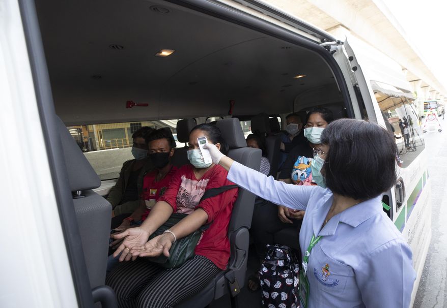 Health officer check temperature passenger in van at a health check point in Bangkok, Thailand, Thursday, March 26, 2020. It is the first day of month long state of emergency enforced in Thailand to allow its government to impose stricter measures to control the coronavirus that has infected hundreds of people in the Southeast Asian country. (AP Photo/Sakchai Lalit)