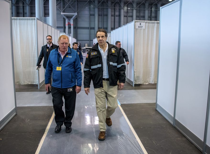 In this Friday, March 27, 2020, photo provided by Office of Governor Andrew M. Cuomo, Gov. Andrew Cuomo, right, walks the corridor of a nearly completed makeshift hospital erected by the U.S. Army Corps of Engineers at the Jacob Javits Convention Center in New York. Cuomo said the state wants to build four more temporary hospitals in New York City within weeks, before coronavirus cases are projected to peak. (Darren McGee/Office of Governor Andrew M. Cuomo via AP)