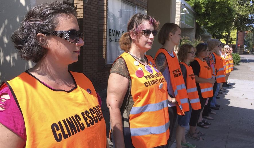 In this July 17, 2017 file photo, escort volunteers line up outside the EMW Women&#39;s Surgical Center in Louisville, Ky., the state&#39;s only abortion clinic. On March 31, 2020, the AP reported that a Wichita, Kan.-area official wants to temporarily close an abortion clinic to curb the spread of the coronavirus that has sickened residents and staff at another Kansas nursing home. (AP Photo/Dylan Lovan, File) **FILE**