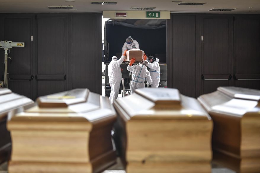 In this file photo, coffins arrive from the Bergamo area, where the coronavirus infections caused many victims, are being unloaded from a military truck that transported them in the cemetery of Cinisello Balsamo, near Milan in Northern Italy, Friday, March 27, 2020.   (Claudio Furlan/LaPresse via AP) **FILE**