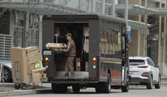 FILE - In this Thursday, March 26, 2020 file photo, a United Parcel Service driver loads boxes during a delivery in downtown Seattle. Amid the coronavirus outbreak, UPS and FedEx have stopped requiring signatures for packages. (AP Photo/Ted S. Warren)