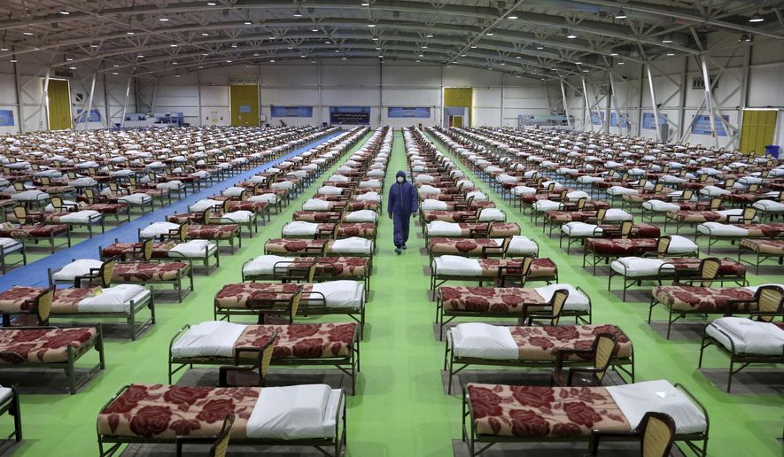 A member of the Iranian army walks past rows of beds at a temporary 2,000-bed hospital for COVID-19 coronavirus patients set up by the army at the international exhibition center in northern Tehran, Iran, on Thursday, March 26, 2020. (AP Photo/Ebrahim Noroozi)