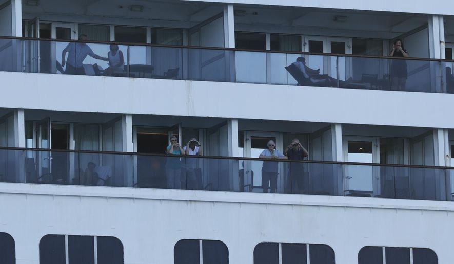Passengers look out from the Zaandam cruise ship, anchored in the bay of Panama City, Friday, March 27, 2020. Several passengers have died aboard the cruise ship and a few people aboard the ship have tested positive for the new coronavirus, the cruise line said Friday, with hundreds of passengers unsure how long they will remain at sea. (AP Photo/Arnulfo Franco)