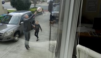 In this Thursday, March 19, 2020, photo, Frankie Keenan shoots baskets with his daughter Rachel, 9, at their home in San Francisco. California&#39;s Bay Area has been shut down for more than a week, the first region of America to order its residents to stay home, work remotely and homeschool their children in a desperate bid to slow the spread of the coronavirus pandemic. (AP Photo/Jeff Chiu)