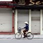 A woman cycles past closed shops in Hanoi, Vietnam, Friday, March 27, 2020. Vietnam&#39;s Prime Minister Nguyen Xuan Phuc has ordered to shut down non-essential business to curb the spread of COVID-19. The new coronavirus causes mild or moderate symptoms for most people, but for some, especially older adults and people with existing health problems, it can cause more severe illness or death. (AP Photo/Hau Dinh)