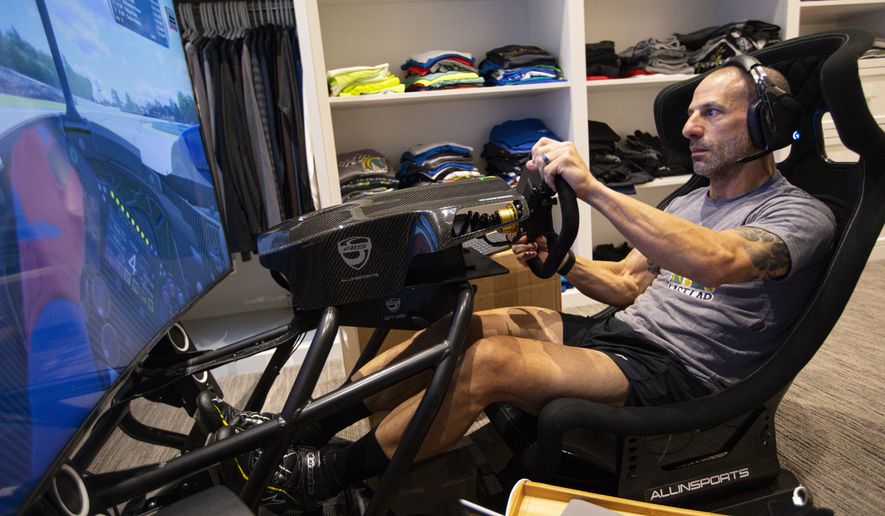 IndyCar driver Tony Kanaan, of Brazil, practices on his racing simulator in his home in Indianapolis, Saturday, March 28, 2020. Kanaan, along with other IndyCar drivers and NASCAR's Jimmie Johnson will compete in the series' inaugural virtual racing event Saturday. (AP Photo/Michael Conroy)