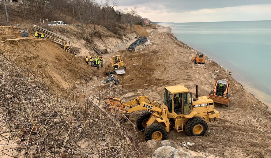 In this Jan. 2020 photo provided by Geof Benson, crews use bulldozers to move sand along Lake Michigan's shoreline in Beverly Shores, Ind., in  to protect local beaches from storms that have scoured the region's shoreline during a period of near record high water levels. Leaders of several of Indiana's lakeside communities, including Beverly Shores, have urged Gov. Eric Holcomb to declare a state of emergency and help with funding to fight erosion that's eating away at beaches important to local tourism and threatening beachside homes. (Courtesy of Geof Benson via AP)