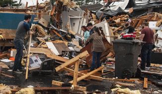 A group of people help clear debris and salvage items from Pawn Depot after a tornado touched down Saturday, March 28, 2020, in Jonesboro, Ark. (Quentin Winstine/The Jonesboro Sun via AP)