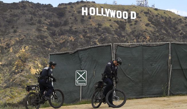 Los Angeles police officers patrol near the Hollywood Sign, Saturday, March 28, 2020, in Los Angeles. With cases of coronavirus surging and the death toll surpassing 100, lawmakers are pleading with cooped-up Californians to spend a second weekend at home to slow the spread of the infections. It has been more than a week since Gov. Gavin Newsom barred 40 million residents from going outdoors except for essentials. Even so, reports of crowds have prompted local and state officials to warn that ignoring social distancing, park and beach closures could spread the virus, which already is surging.  (AP Photo/Mark J. Terrill)