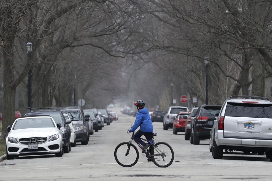 A resident rides his bicycle on the street in Evanston, Ill., Friday, March 27, 2020. The conservative watchdog group Judicial Watch filed the class-action suit last month against Evanston, Illinois. The city of about 75,000 people outside Chicago in Cook County became the first locality in 2021 to implement a reparations program for Black people. (AP Photo/Nam Y. Huh)