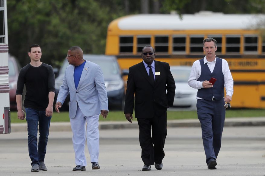 Pastor Tony Spell, right, walks with others after services at the Life Tabernacle Church in Central, La., Sunday, March 29, 2020. Spell has defied a shelter-in-place order by Louisiana Gov. John Bel Edwards, due to the new coronavirus pandemic, and continues to hold church services with hundreds of congregants. (AP Photo/Gerald Herbert)