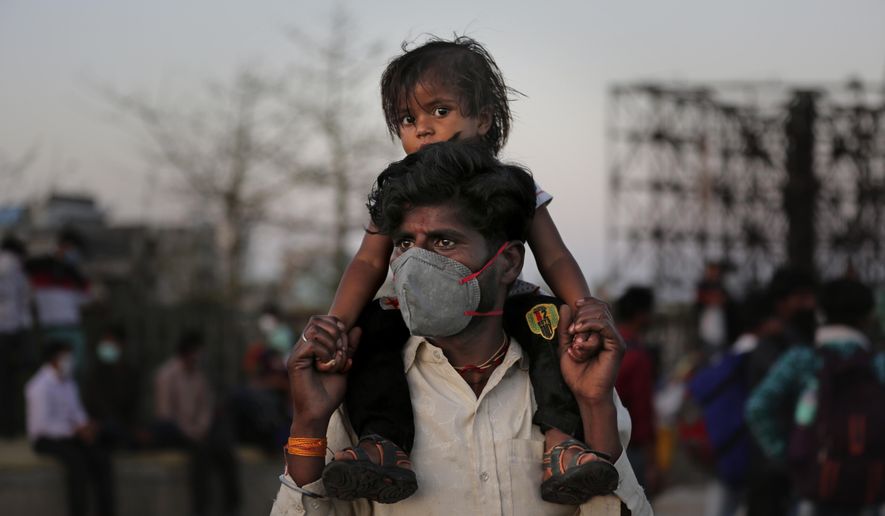 An Indian migrant worker carries a child on his shoulders as they wait for transportation to their village following a lockdown amid concern over spread of coronavirus in New Delhi, India, Saturday, March 28, 2020. Authorities sent a fleet of buses to the outskirts of India&#x27;s capital on Saturday to meet an exodus of migrant workers desperately trying to reach their home villages during the world&#x27;s largest coronavirus lockdown. Thousands of people, mostly young male day laborers but also families, fled their New Delhi homes after Prime Minister Narendra Modi announced a 21-day lockdown that began on Wednesday and effectively put millions of Indians who live off daily earnings out of work. (AP Photo/Altaf Qadri)