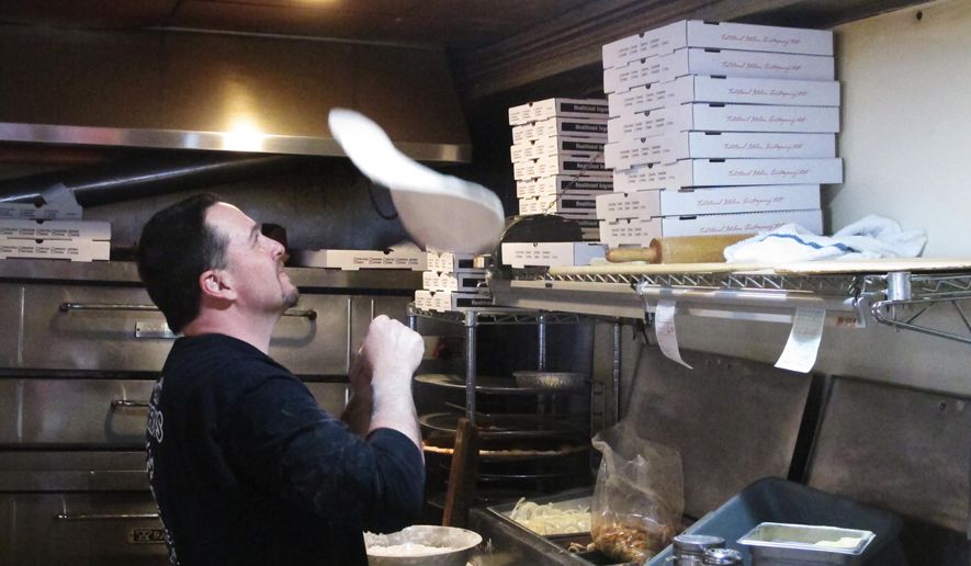 In this March 24, 2020, photo, Michael Morin, co-owner of Federico's Pizza in Belmar N.J., makes a pizza. Morin and his brother Bryan took out a $50,000 line of credit to ensure that their 20 employees can stay on the payroll for at least two months during the virus outbreak. That prompted an outpouring of donations from customers wanting to send pizzas to hospital workers and first responders. (AP Photo/Wayne Parry)