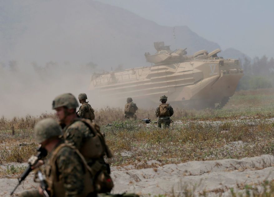 In this April 21, 2015, file photo, U.S. troops take positions as an amphibious assault vehicle maneuvers during an annual U.S.-Philippines joint military drill at the Naval Education and Training Command at San Antonio township, Zambales province, northwest of Manila, Philippines. Amphibious military capabilities are on the agenda the week of May 18, 2015, as the U.S. Marine Corps and Navy host defense leaders from around the Pacific in Hawaii. (AP Photo/Bullit Marquez, File)