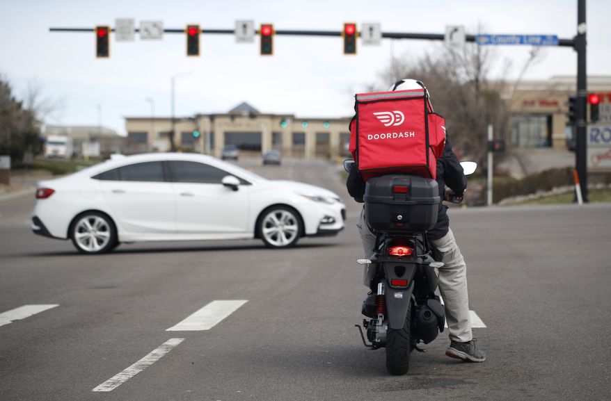 A food delivery rider waits for the traffic light to change to head northbound on Chester Street at County Line Road as a statewide stay-at-home order remains in effect in an effort to reduce the spread of the new coronavirus Monday, March 30, 2020, in Lone Tree, Colo. The new coronavirus causes mild or moderate symptoms for most people, but for some, especially older adults and people with existing health problems, it can cause more severe illness or death. (AP Photo/David Zalubowski)