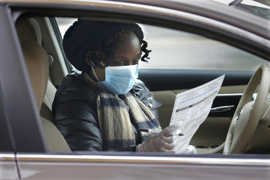 FILE - In this Saturday, March 28, 2020, file photo, Brenda Jones checks over her ballot as she votes absentee during drive-up early voting in Milwaukee. Preparations for Wisconsin's presidential primary and spring election that's just a week away on April 7 continue, even in the face of a growing number of COVID-19 cases statewide and lawsuits seeking a delay and other changes to how the election is run. Monday, March 30, 2020 is the deadline for voters to register to vote absentee. (Rick Wood/Milwaukee Journal-Sentinel via AP)