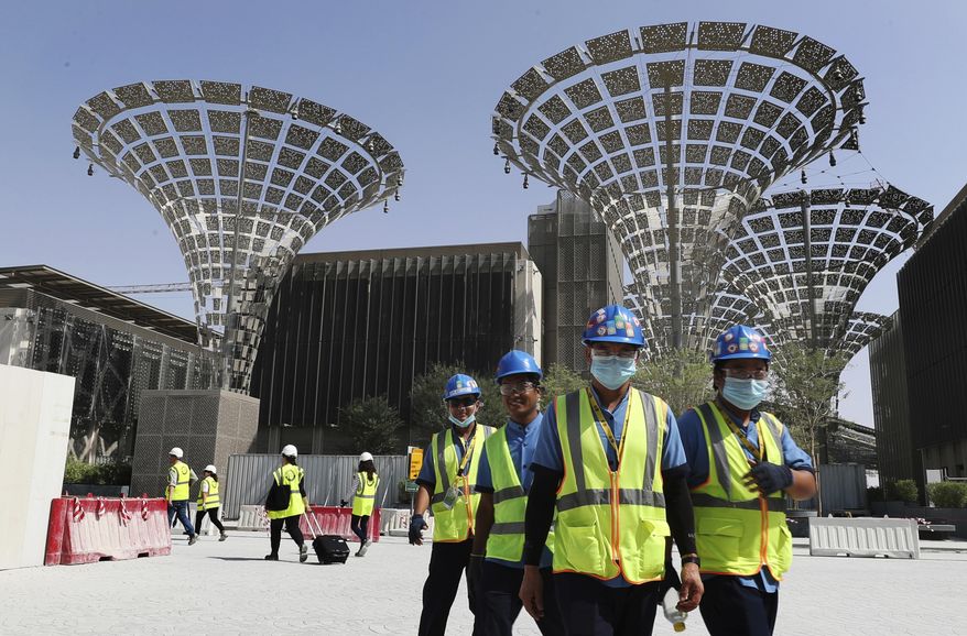 FILE - In this Oct. 8, 2019 file photo, technicians walk at the under construction site of the Expo 2020 in Dubai, United Arab Emirates. On Monday, March 30, 2020, the organizers of Expo 2020 recommended postponing the world's fair until next years over the new coronavirus pandemic. Dubai has already spent billions of dollars on the world's fair, which was supposed to take place in October. The ultimate decision over the event will be made by the Paris-based Bureau International des Expositions, which had awarded the fair to Dubai in 2014. (AP Photo/Kamran Jebreili, File)