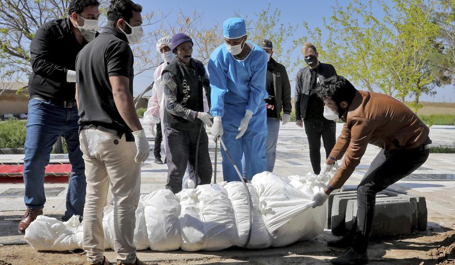 People wearing protective clothings, masks and gloves, attend the funeral of a victim who died after being infected with the new coronavirus, at a cemetery just outside Tehran, Iran, Monday, March 30, 2020.The new coronavirus causes mild or moderate symptoms for most people, but for some, especially older adults and people with existing health problems, it can cause more severe illness or death. (AP Photo/Ebrahim Noroozi)