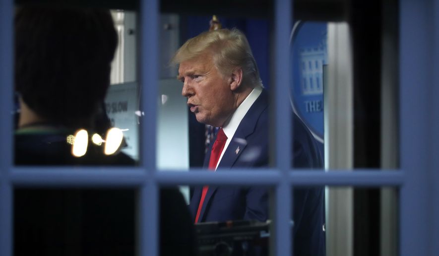 As seen through a window, President Donald Trump speaks about the coronavirus in the James Brady Press Briefing Room of the White House, Tuesday, March 31, 2020, in Washington. (AP Photo/Alex Brandon)