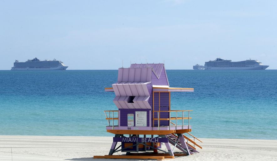 Two cruise ships are anchored offshore past a lifeguard tower, Tuesday, March 31, 2020, in Miami Beach, Fla. (AP Photo/Wilfredo Lee)