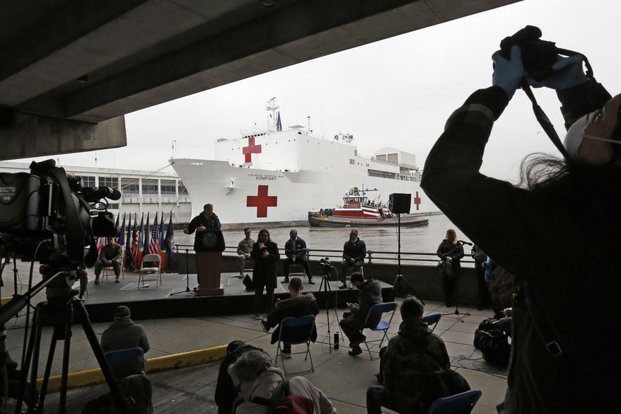 A journalist records speakers at a press briefing following the arrival of the USNS Comfort, a naval hospital ship with a 1,000 bed-capacity, Monday, March 30, 2020, at Pier 90 in New York. The ship will be used to treat patients who do not have the new coronavirus as land-based hospitals fill up to capacity with those that do. (AP Photo/Kathy Willens)