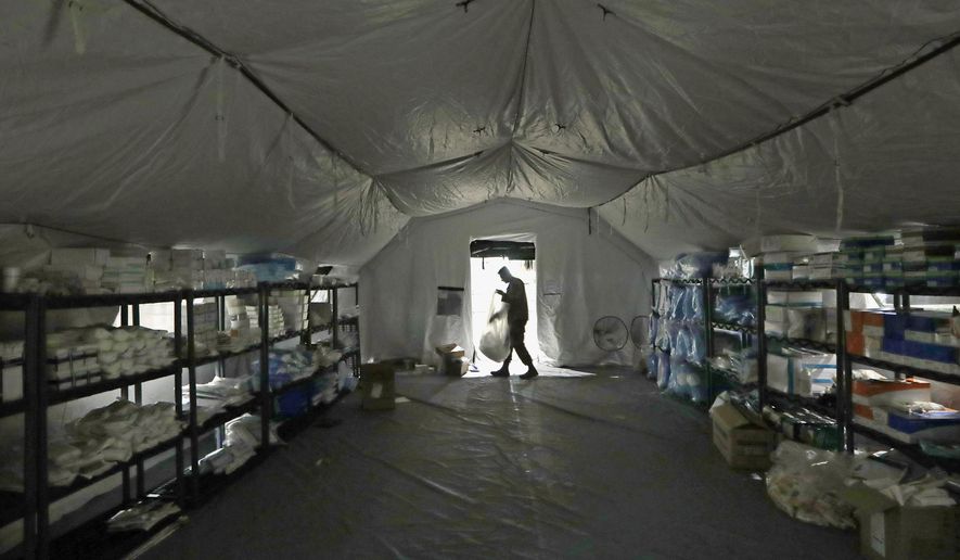 A U.S. Army soldier walks inside a mobile surgical unit being set up by soldiers from Fort Carson, Col., and Joint Base Lewis-McChord (JBLM) as part of a field hospital inside CenturyLink Field Event Center, Tuesday, March 31, 2020, in Seattle. Soldiers from the 627th Army Hospital at Fort Carson, will join soldiers from JBLM to staff the 250-bed hospital to be used for non-COVID-19 cases, allowing local hospitals additional space for patients affected by the coronavirus outbreak. Officials said that the field hospital is expected to be ready to receive patients next week. (AP Photo/Elaine Thompson)