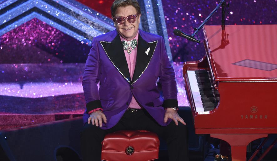 FILE - In this Sunday, Feb. 9, 2020, file photo, Elton John appears after performing his nominated song, "(I'm Gonna) Love Me Again," at the Oscars in Los Angeles. The Elton John-led starry benefit concert that featured Billie Eilish, Mariah Carey and Alicia Keys on Sunday has raised nearly $8 million to battle the coronavirus. The musicians performed from their homes for the hour-long event that aired on Fox and iHeartMedia radio stations. The money will go to Feeding America and First Responders Children’s Foundation. (AP Photo/Chris Pizzello, File)