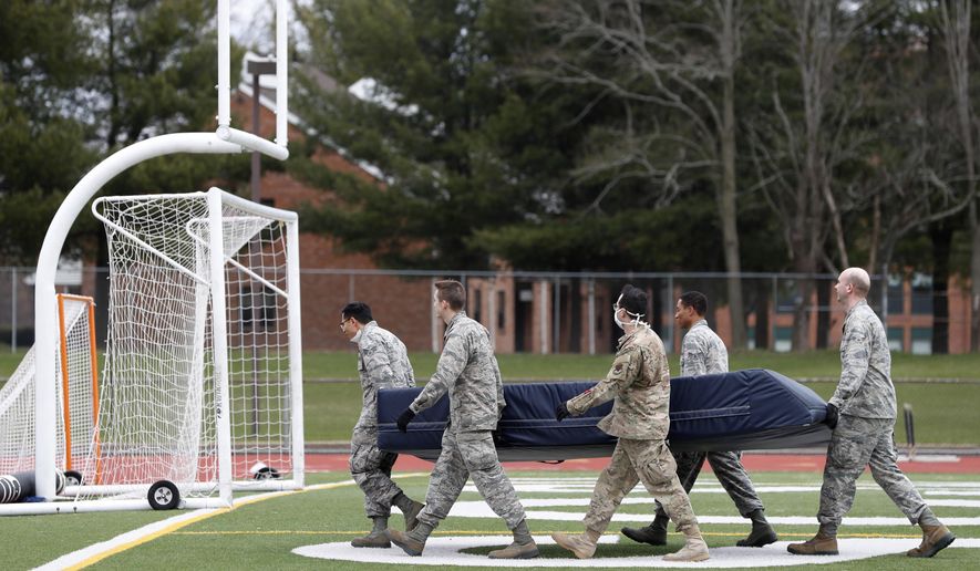 Members of the Connecticut National Guard move sports equipment from a field house to a football and soccer field before unloading supplies for a "surge" hospital that is being constructed to help out during the current coronavirus crisis, Tuesday, March 31, 2020, at Southern Connecticut State University in New Haven. The 250-bed field hospital will facilitate overflow in the event that regional hospitals treating COVID-19 patients reach capacity. (AP Photo/Kathy Willens)
