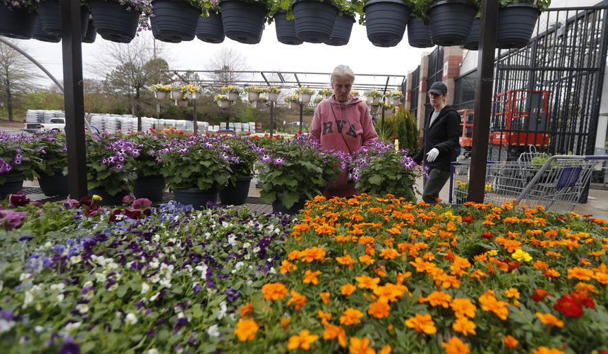 Gail Henrickson, left, and her daughter, Melissa, shop for plants at a local garden center as they stay at home during the coronavirus outbreak Monday March 23 , 2020, in Richmond, Va. The two work at a local restaurant that has closed down and are doing their spring gardening. (AP Photo/Steve Helber)