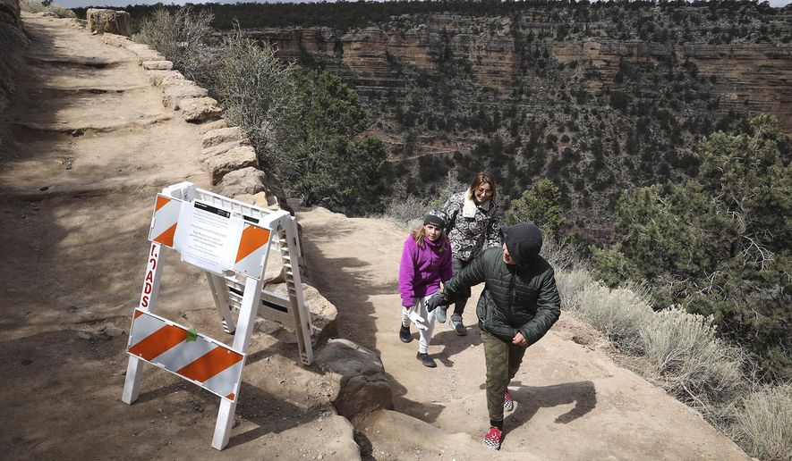 In this March 27, 2020 photo, Shelly Clayton, center, walks up the Bright Angel Trail at Grand Canyon National Park, Ariz., with her children Audrey Kuhar, 11, left, and Cooper Kuhar, 11. The park has closed restaurants, lodges, visitor centers, campgrounds and other services as it awaits approval from the federal government for a full shutdown. (Jake Bacon/Arizona Daily Sun via AP)