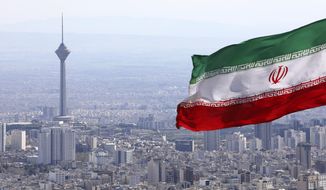 Iran&#39;s national flag waves as Milad telecommunications tower and buildings are seen in Tehran, Iran, Tuesday, March 31, 2020. In recent days, Iran which is battling the worst new coronavirus outbreak in the region, has ordered the closure of nonessential businesses and banned intercity travels aimed at preventing the virus&#39; spread.   (AP Photo/Vahid Salemi)