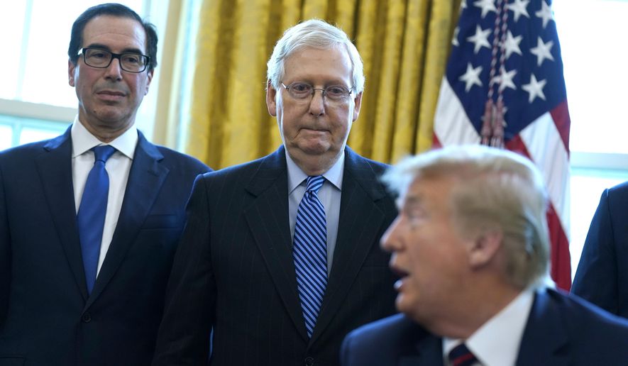 Treasury Secretary Steven Mnuchin and Senate Majority Leader Mitch McConnell, R-Ky., listen as President Donald Trump speaks before he signs the coronavirus stimulus relief package in the Oval Office at the White House, Friday, March 27, 2020, in Washington. (AP Photo/Evan Vucci)