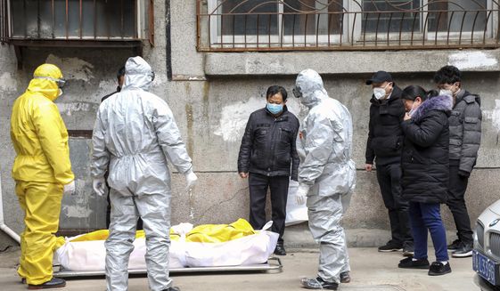 FILE - In this Feb. 1, 2020, file photo, funeral home workers remove the body of a person suspected to have died from the coronavirus outbreak from a residential building in Wuhan in central China&#39;s Hubei Province. Skepticism about China’s reported coronavirus cases and deaths has swirled throughout the crisis, fueled by official efforts to quash bad news in the early days and a general distrust of the government. In any country, getting a complete picture of the infections amid the fog of war is virtually impossible. (Chinatopix via AP, File)