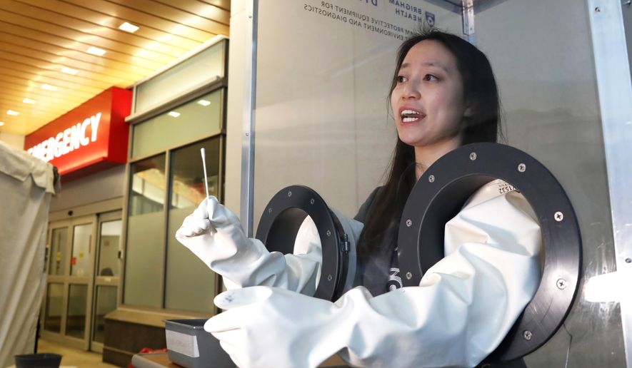 Dr. Sherry Yu demonstrates a free-standing booth for COVID-19 testing, Wednesday, April 1, 2020, at Brigham &amp;amp; Women&#39;s Hospital in Boston. The isolation booths were created by a collaboration of the hospital&#39;s clinical leaders and engineering team, inspired by a South Korean research design. The booths separate clinicians from patients, protect front line providers, and reduce the need for personal protective equipment. (AP Photo/Elise Amendola)