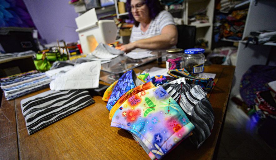 Donna Tosi, of Vernon, Vt., works on making masks for the Brattleboro Retreat in her basement sewing room on March 31, 2020 while watching the news about the COVID-19 outbreak. Tosi has made roughly 135 masks so far. (Kristopher Radder/The Brattleboro Reformer via AP)