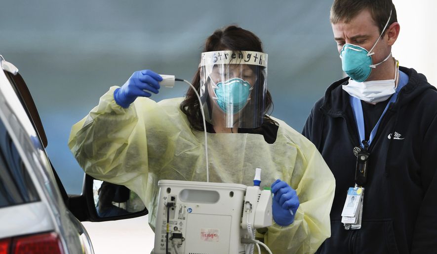 Medical staffers at UNC Hospitals in Chapel Hill, N.C., screen a patient at a drive-thru COVID-19 screening site outside the emergency department. (Scott Sharpe/The News & Observer via AP)